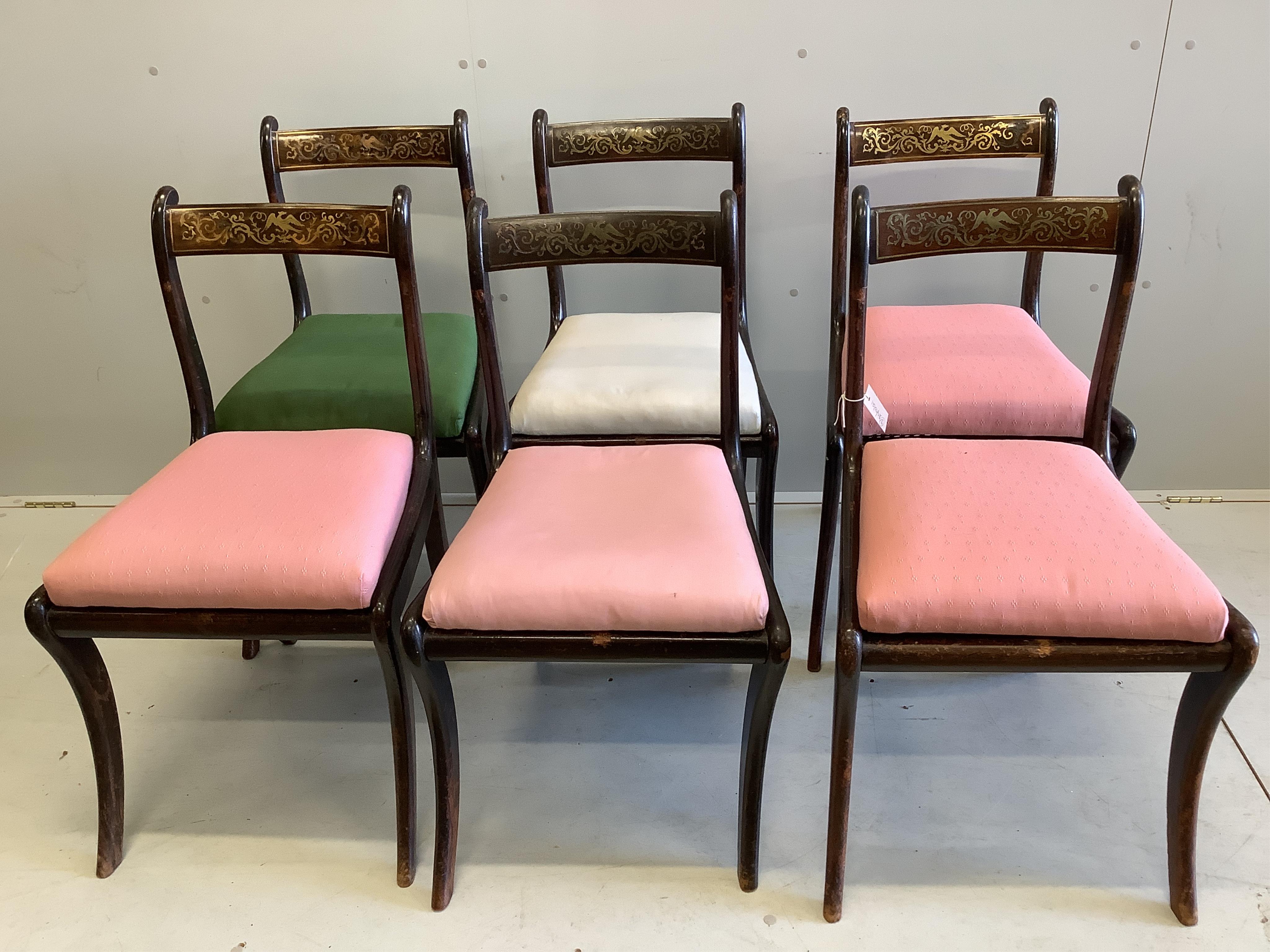 A set of six Regency rosewood and simulated rosewood dining chairs, the top rails inlaid with cut brass decoration, caned seats with slip-in cushions, on sabre legs. Condition - poor